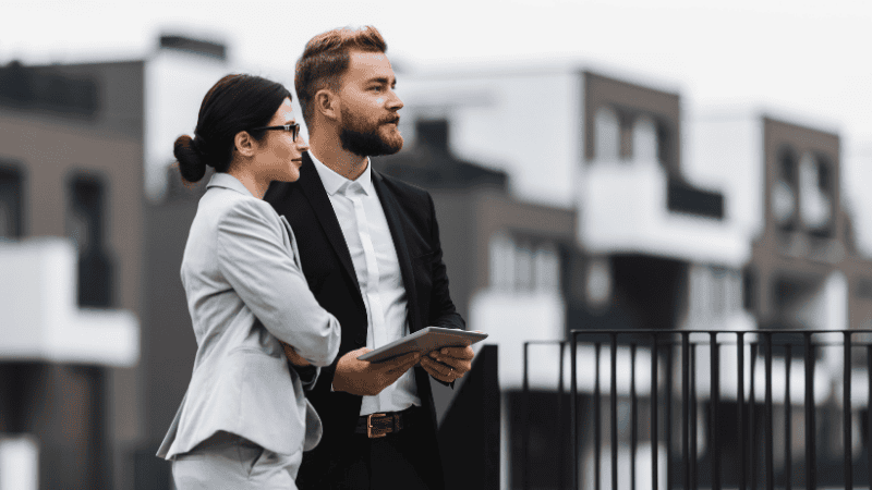 Two real estate agents outside looking at a property - 7 Real Estate Lead Generation Strategies